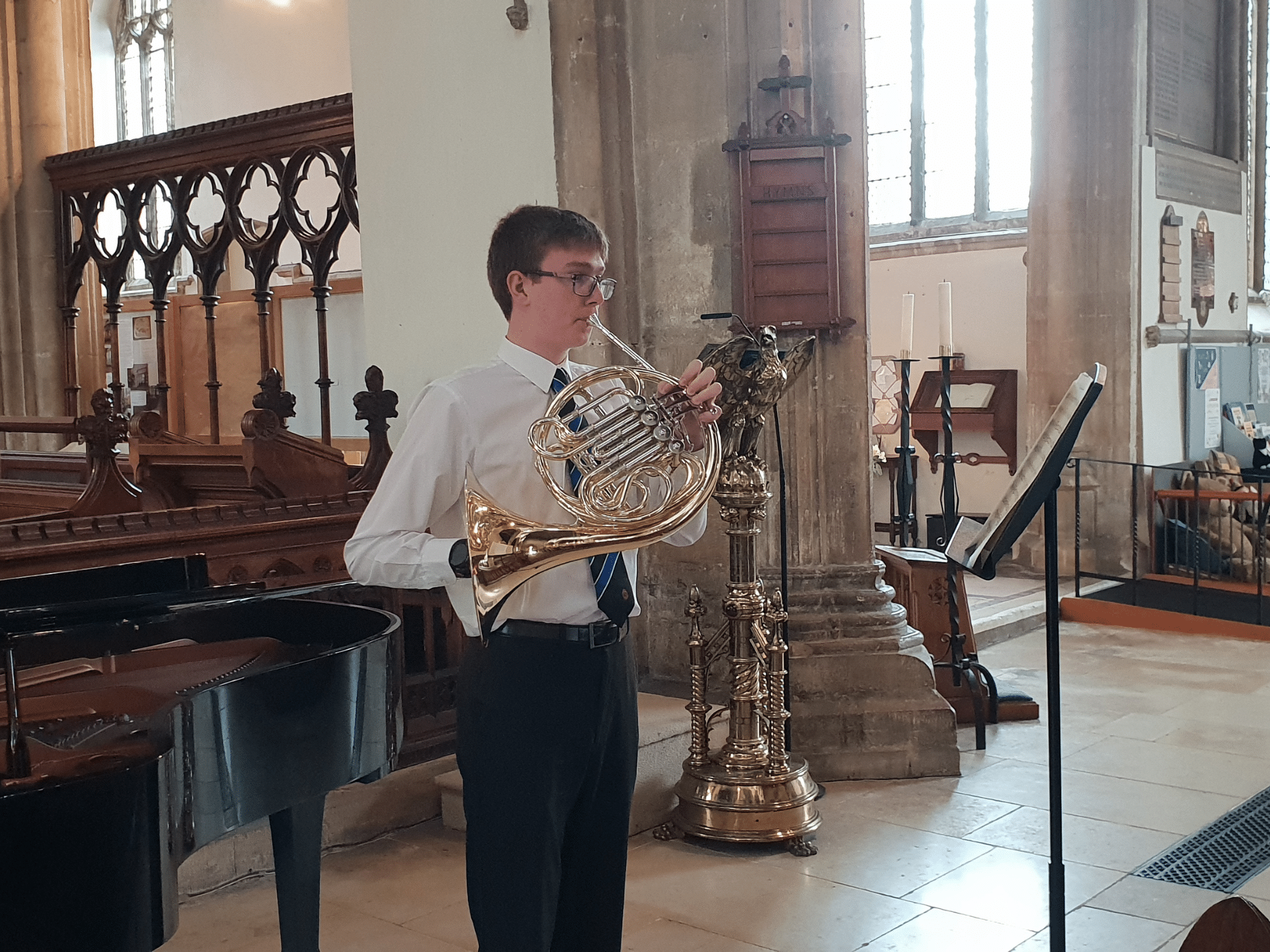 Student plays French horn in recital in church